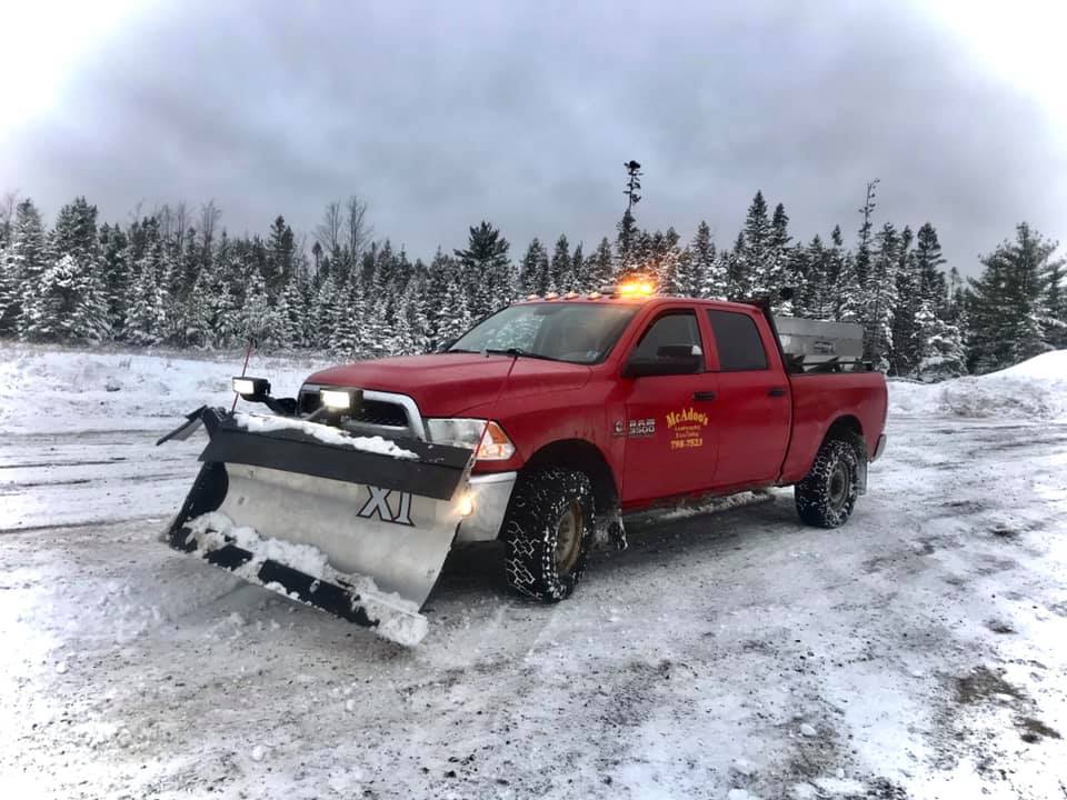 McAdoo's plow truck clearing snow in a driveway